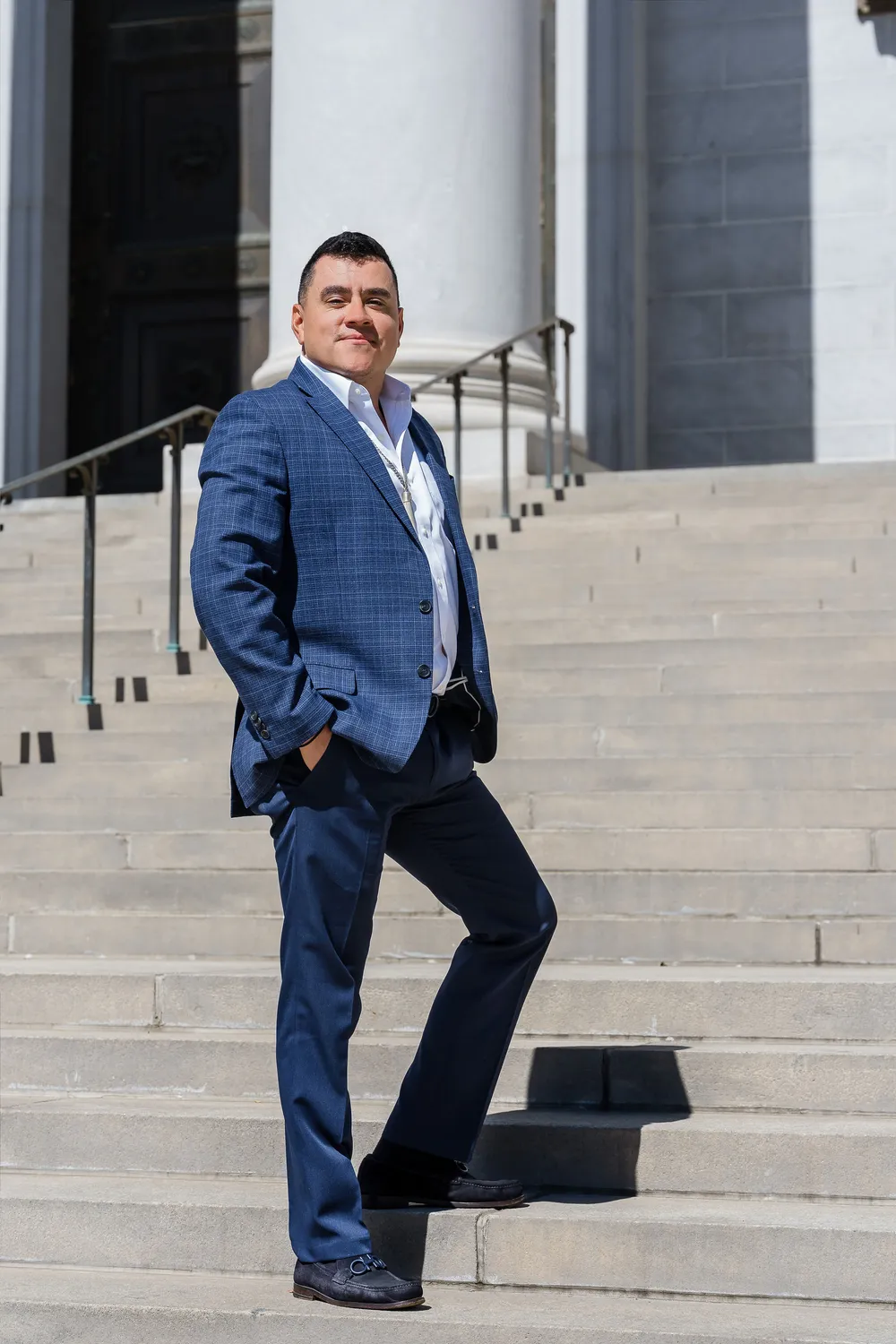 Alfredo Reyes smiling on the steps of the Denver City & County Building