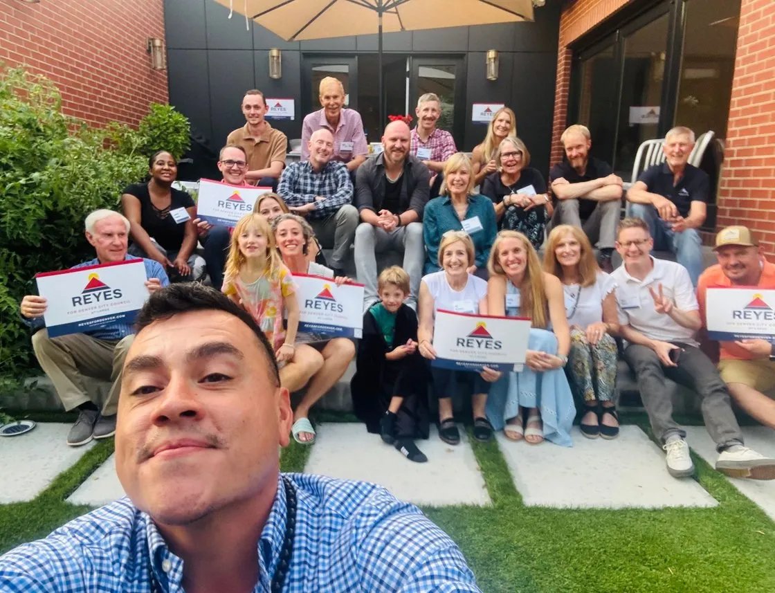 Alfredo with neighbors and supporters holding Reyes signs at a house party