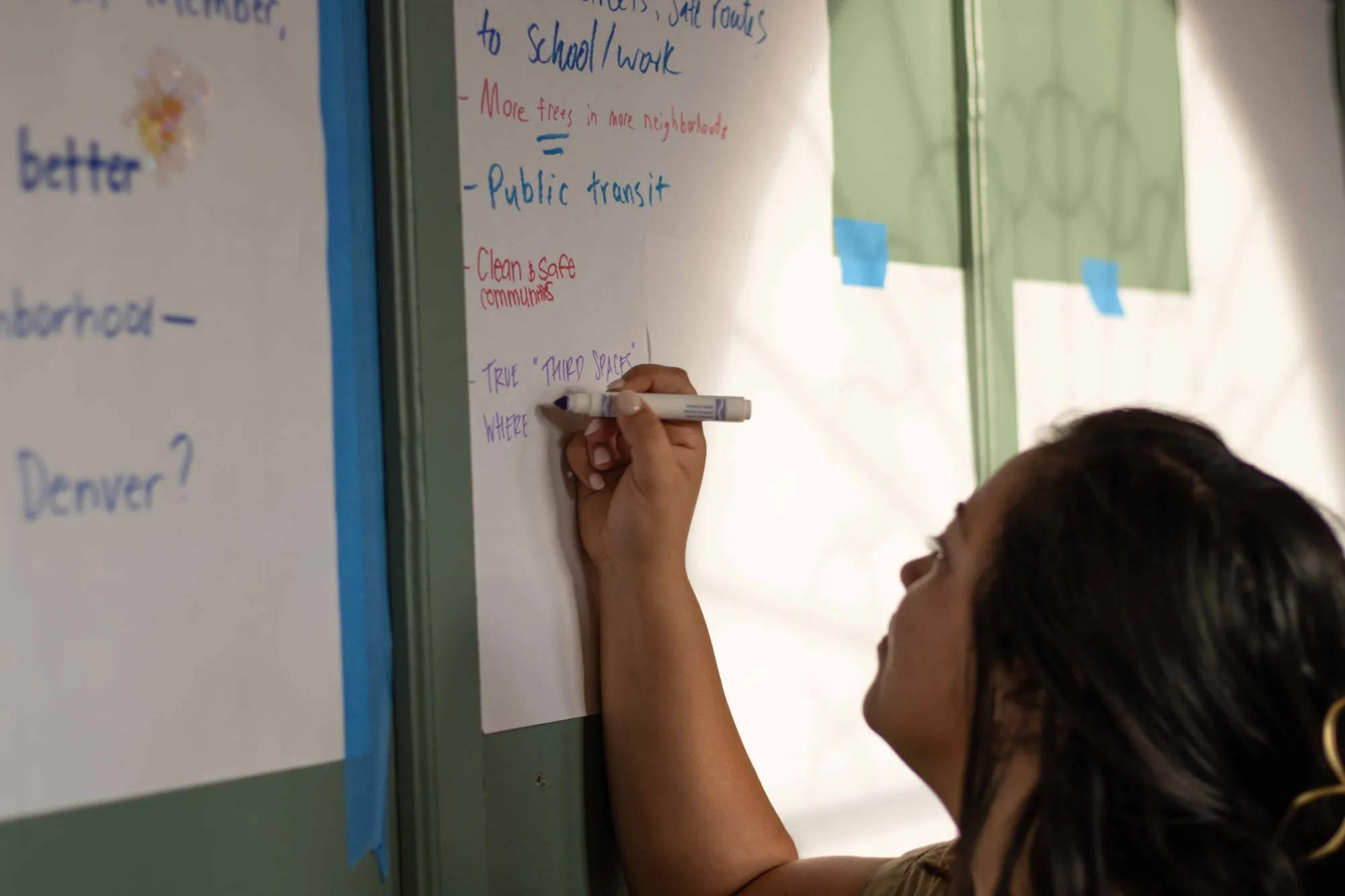 A supporter adding ideas for a thriving Denver to the idea boards at the pavilion